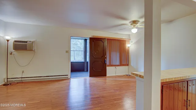 a view of an empty room with wooden floor and a window
