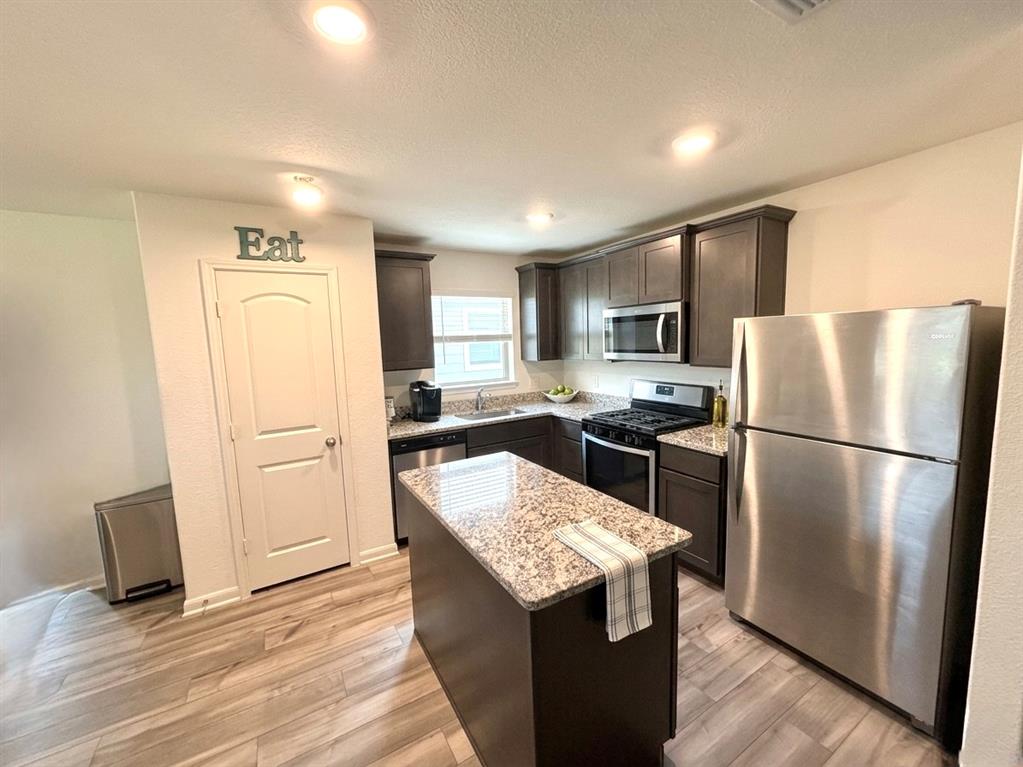 13604 Mineral Road Ponder, TX 76259 - Photo 6 of 20 Kitchen with stainless steel appliances, dark wood finish cabinetry, light stone countertops, light wood-type flooring, and recessed lighting