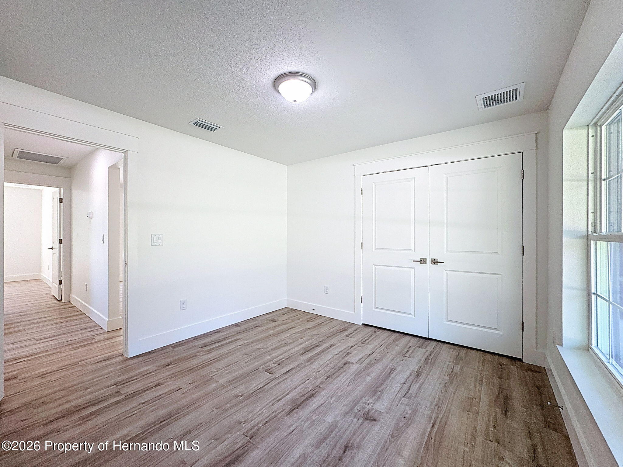 8988 Waterbird Way Weeki Wachee, FL 34613 - Photo 33 of 42 wooden floor in an empty room with a window