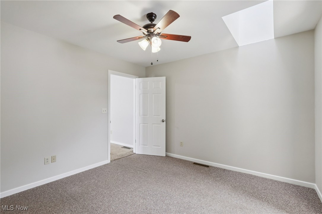 611 Wilson Street Struthers, OH 44471 - Photo 23 of 44 Carpeted empty room featuring a skylight and a ceiling fan