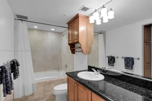 a bathroom with a granite countertop sink a toilet and bathtub