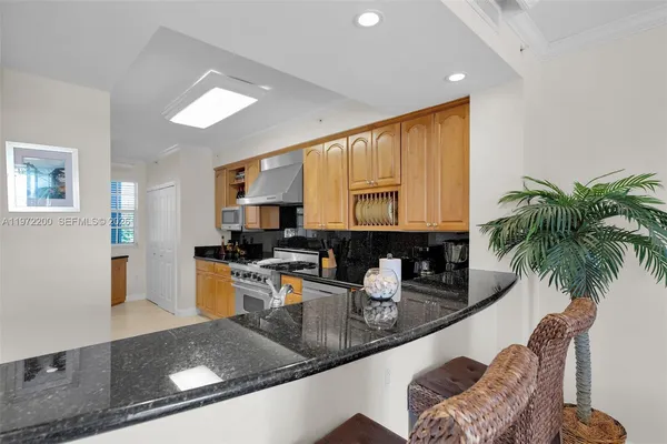 a kitchen with stainless steel appliances granite countertop a sink a stove and a wooden cabinets
