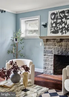 a living room with couches chairs and large windows with a chandelier