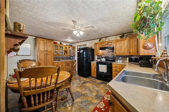 a kitchen with granite countertop a refrigerator a stove a sink a dining table and chairs with wooden floor