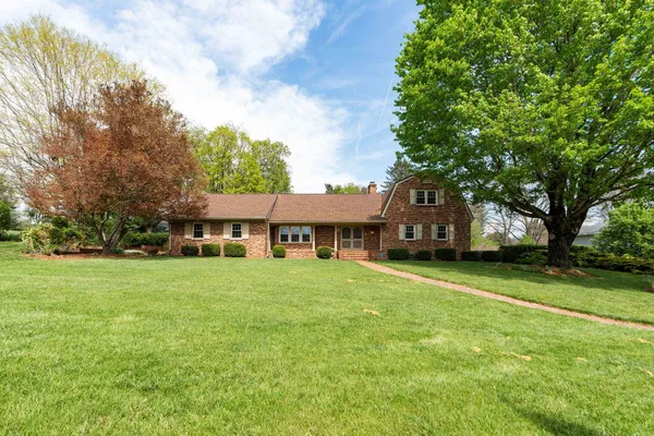 a view of a big house with a big yard and large trees
