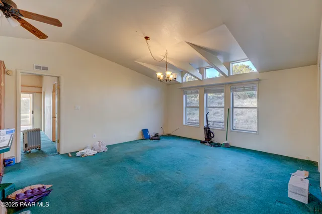 a view of an empty room with window and chandelier fan