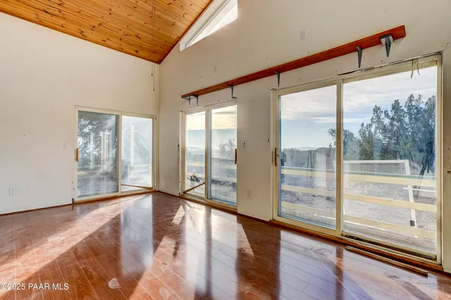 a view of an empty room with window and hardwood floor