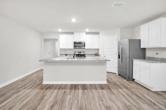 a kitchen with a refrigerator and white cabinets