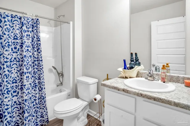 a bathroom with a granite countertop toilet a sink and a mirror