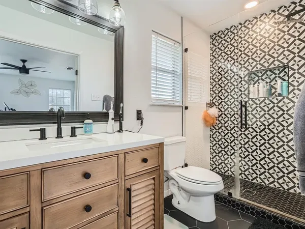 a bathroom with a granite countertop toilet a sink and a mirror