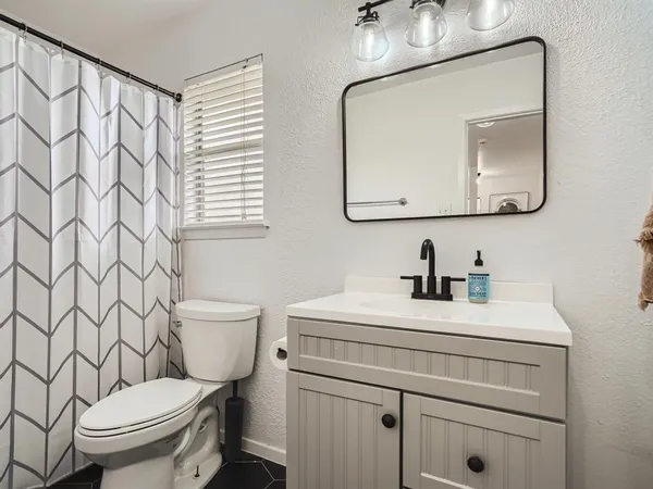 a bathroom with a toilet sink vanity and mirror