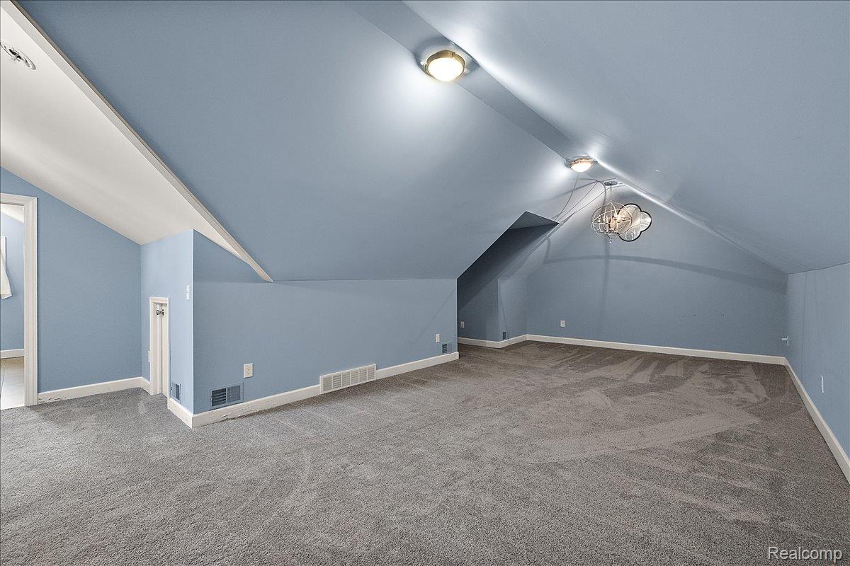 1051 Devonshire Road Grosse Pointe, MI 48230 - Photo 60 of 99 Carpeted room featuring sloped ceilings, two flush-mount ceiling lights, and a decorative pendant light fixture