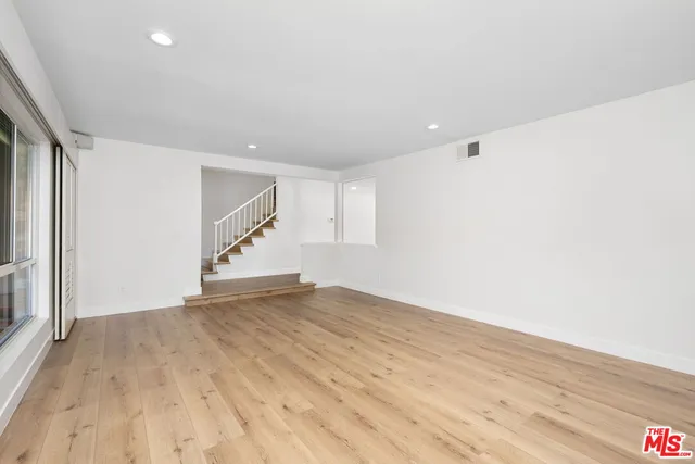 a view of an empty room with wooden floor and stairs