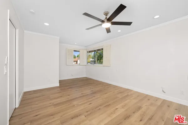 an empty room with wooden floor ceiling fan and windows