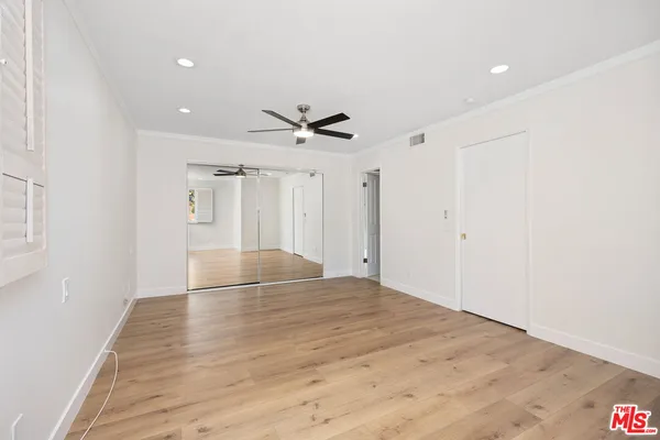 a view of empty room with wooden floor and ceiling fan
