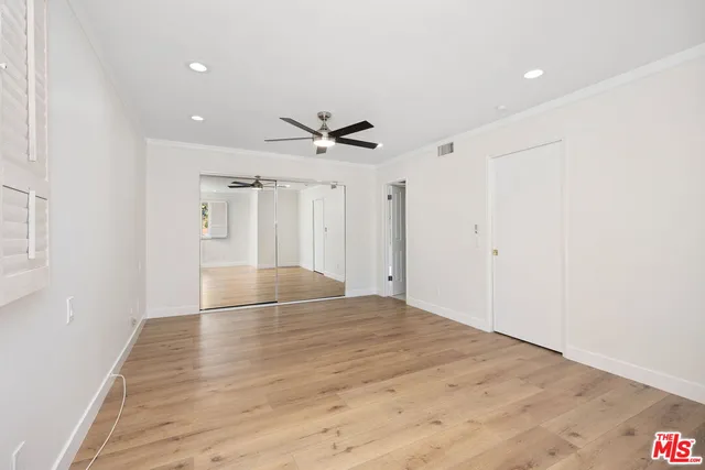 a view of empty room with wooden floor and ceiling fan