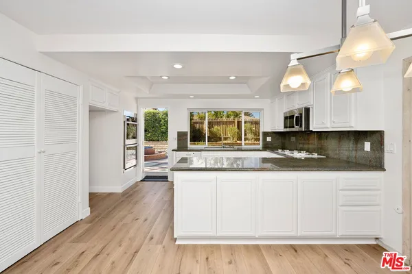 a kitchen with granite countertop a stove and white cabinets