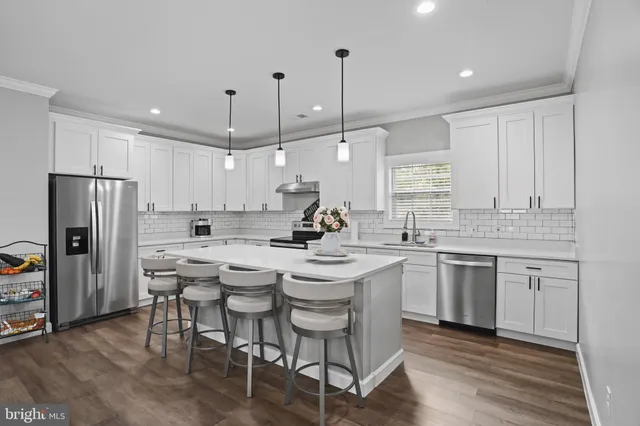 a kitchen with a sink stools a counter space and stainless steel appliances
