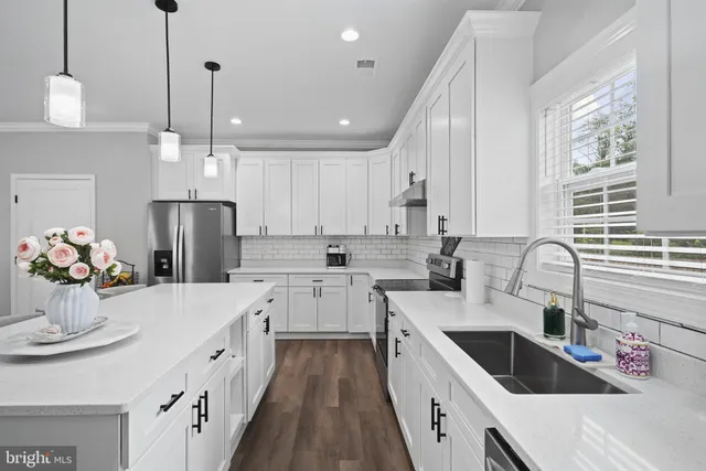 a kitchen with kitchen island granite countertop a sink a counter space appliances and cabinets