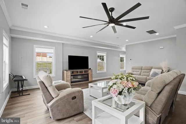 a living room with furniture a ceiling fan and a flat screen tv