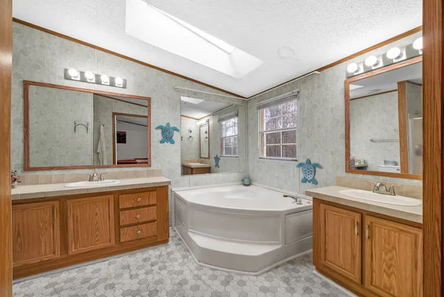 a spacious bathroom with a tub sink and mirror