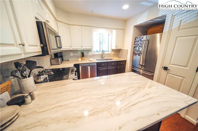 a large white kitchen with sink and a refrigerator