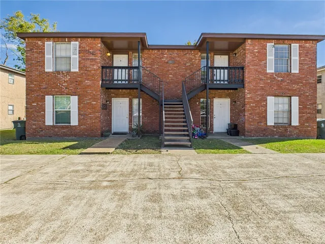 front view of a brick house with a yard