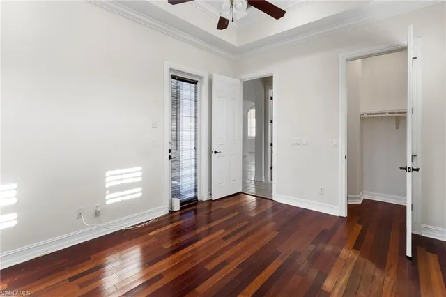 an empty room with wooden floor chandelier fan and windows