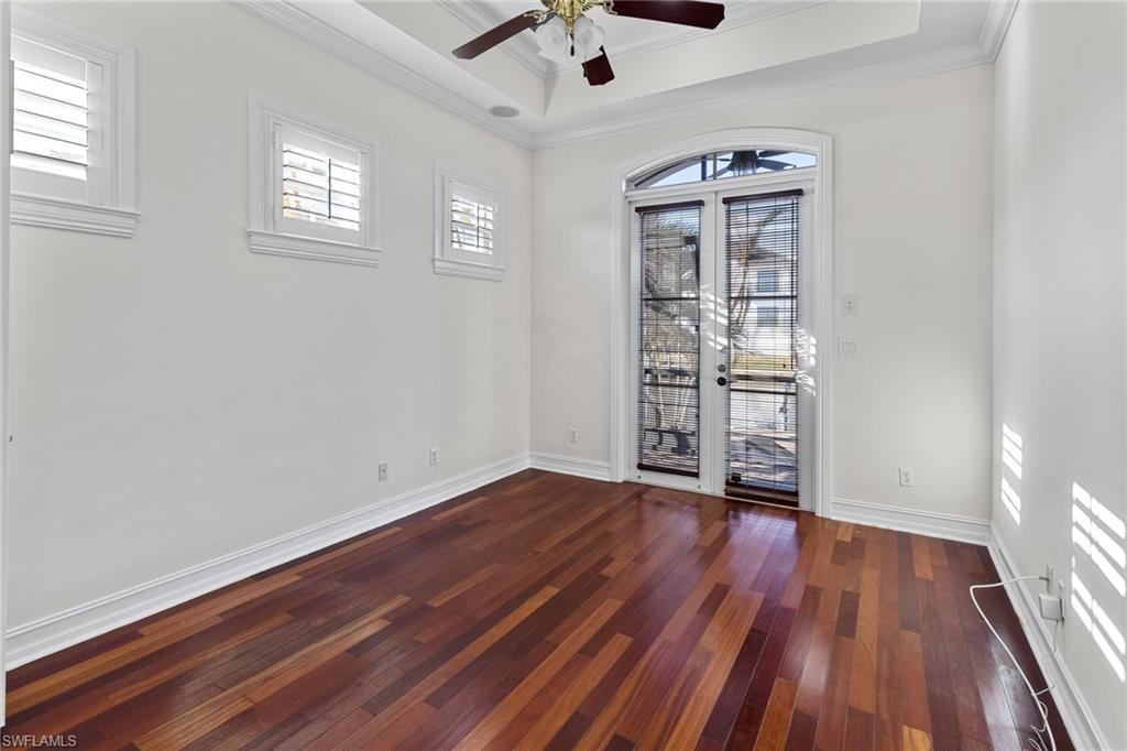 405 Trade Winds Avenue Naples, FL 34108 - Photo 22 of 48 an empty room with wooden floor chandelier fan and windows