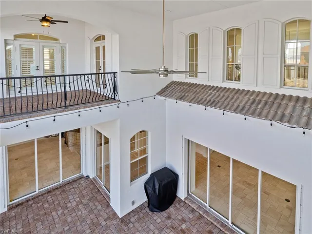 an empty room with a chandelier fan and windows