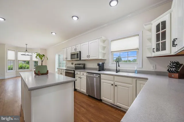 a kitchen with stainless steel appliances granite countertop a stove top oven a sink dishwasher a dining table and chairs with wooden floor