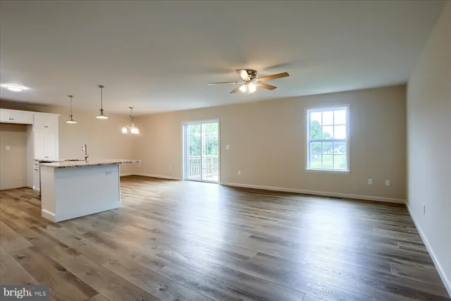 a view of an empty room with a kitchen and wooden floor