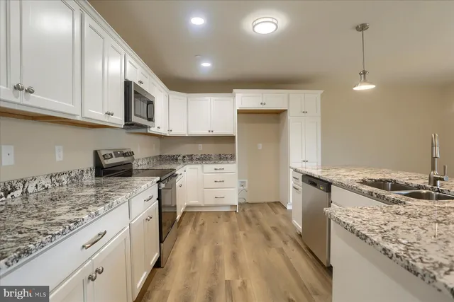 a kitchen with granite countertop a sink stove and refrigerator