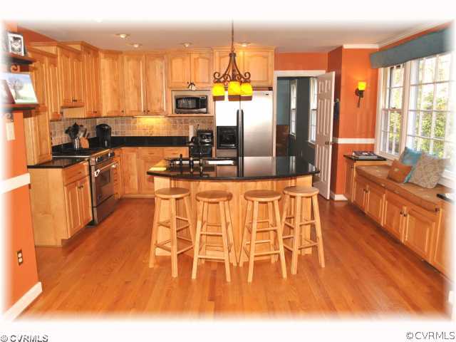 2539 Kentford Road Midlothian, VA 23113 - Photo 5 of 12 a kitchen with stainless steel appliances kitchen island granite countertop a refrigerator a stove top oven and a dining table with wooden floor