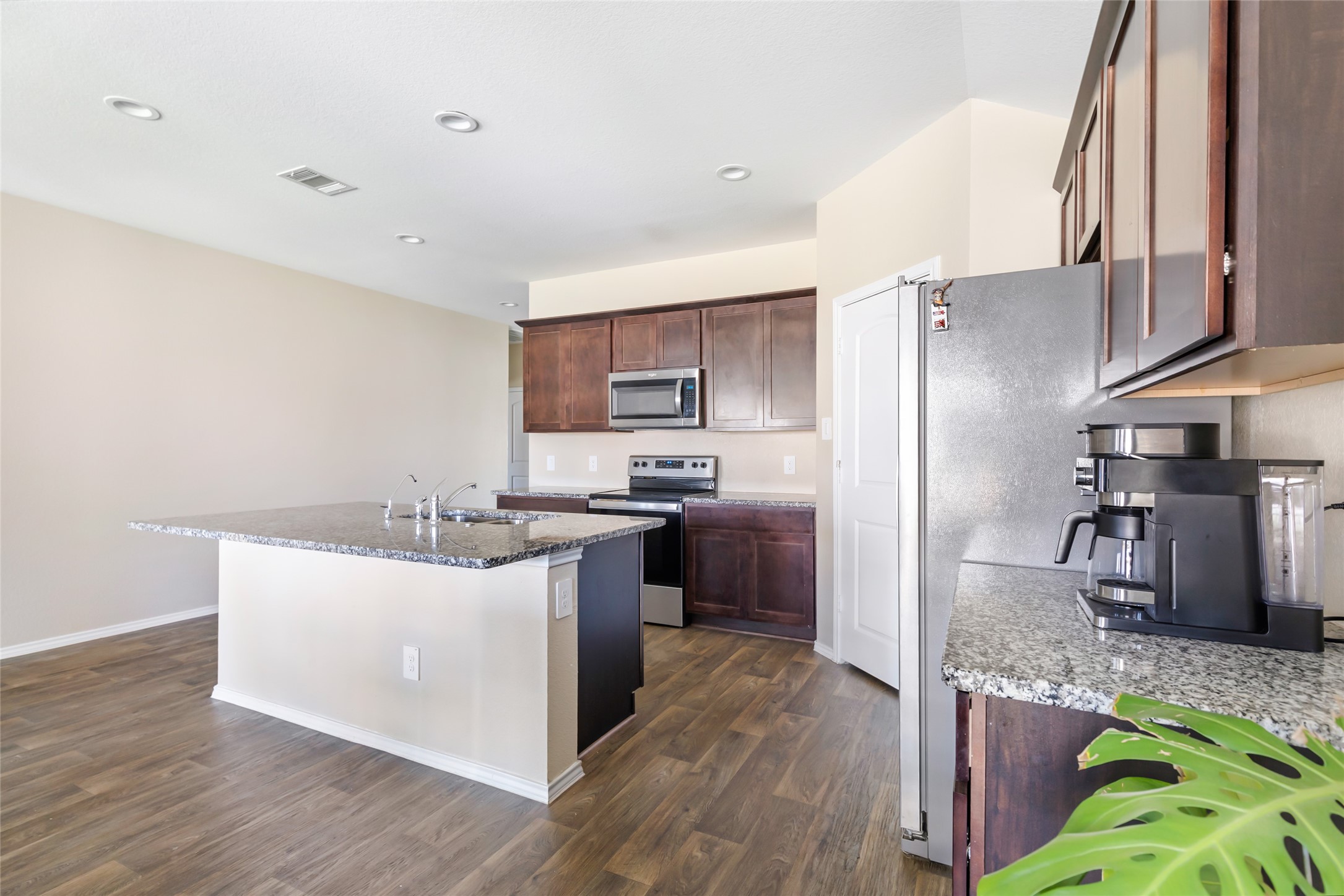 811 Republic Road New Caney, TX 77357 - Photo 27 of 37 Modern kitchen with granite countertops, stainless steel appliances, and dark wood cabinets. Features an island with a sink and open layout with Wood like flooring.