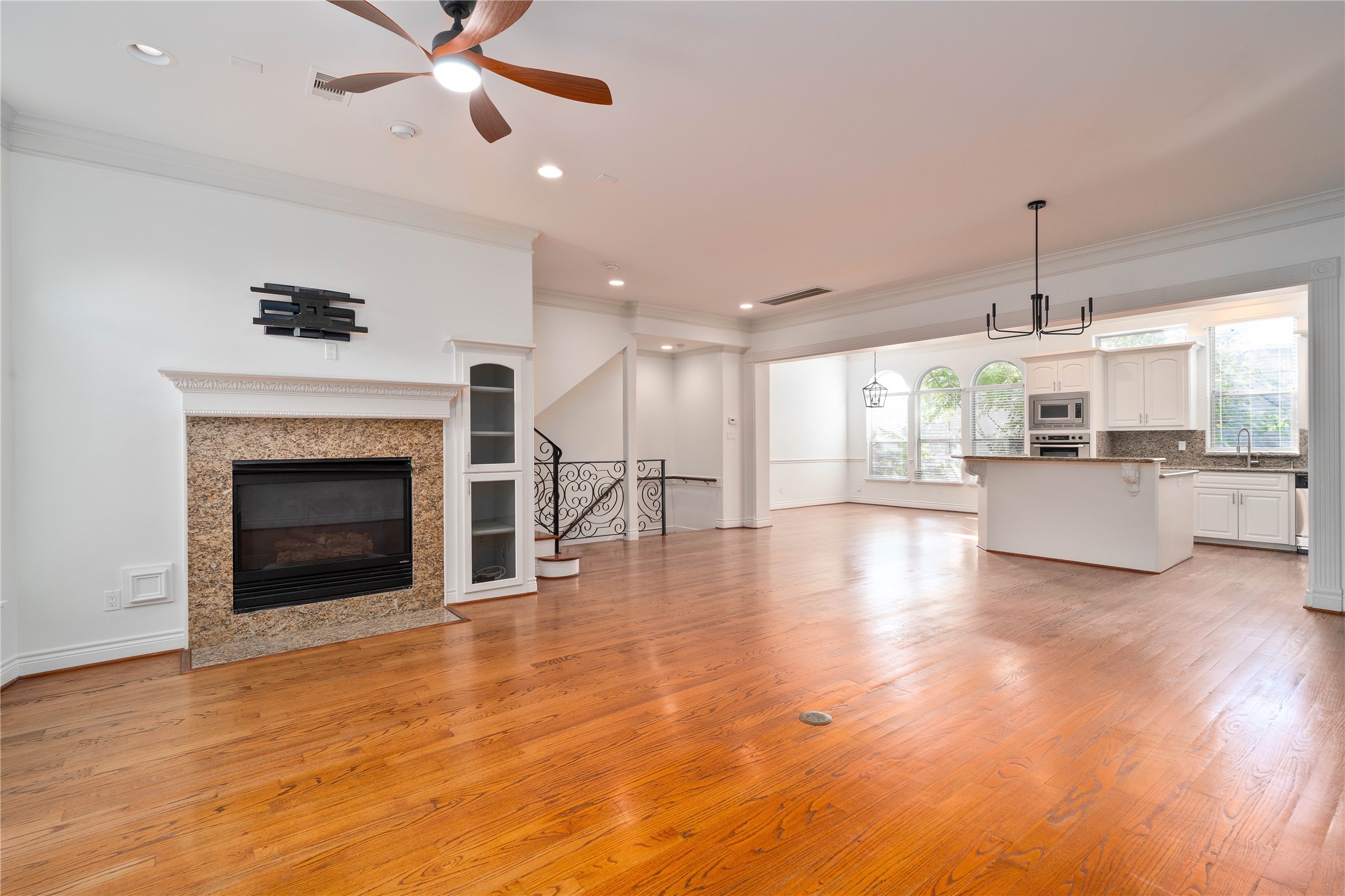 a view of a livingroom with a fireplace a ceiling fan and windows