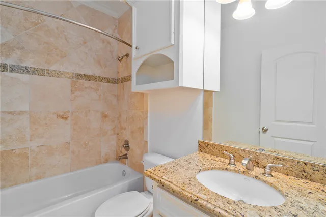 a bathroom with a granite countertop sink toilet and shower