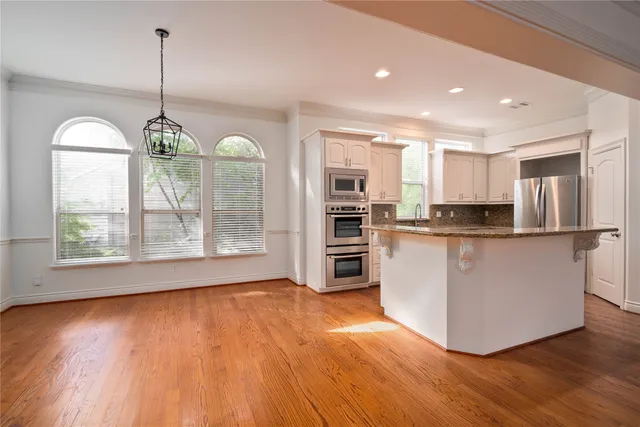 a open kitchen with stainless steel appliances granite countertop a stove top oven a refrigerator with wooden floor and cabinets