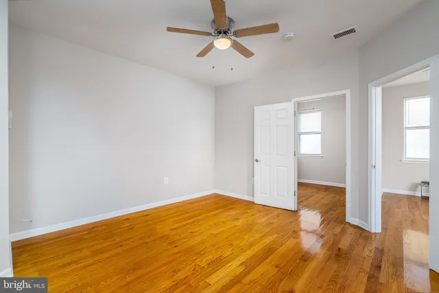 a view of empty room with wooden floor and fan