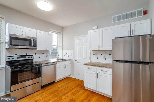a kitchen with white cabinets sink and stainless steel appliances