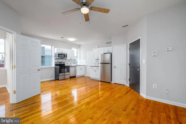 a large white kitchen with refrigerator stove and wooden floor
