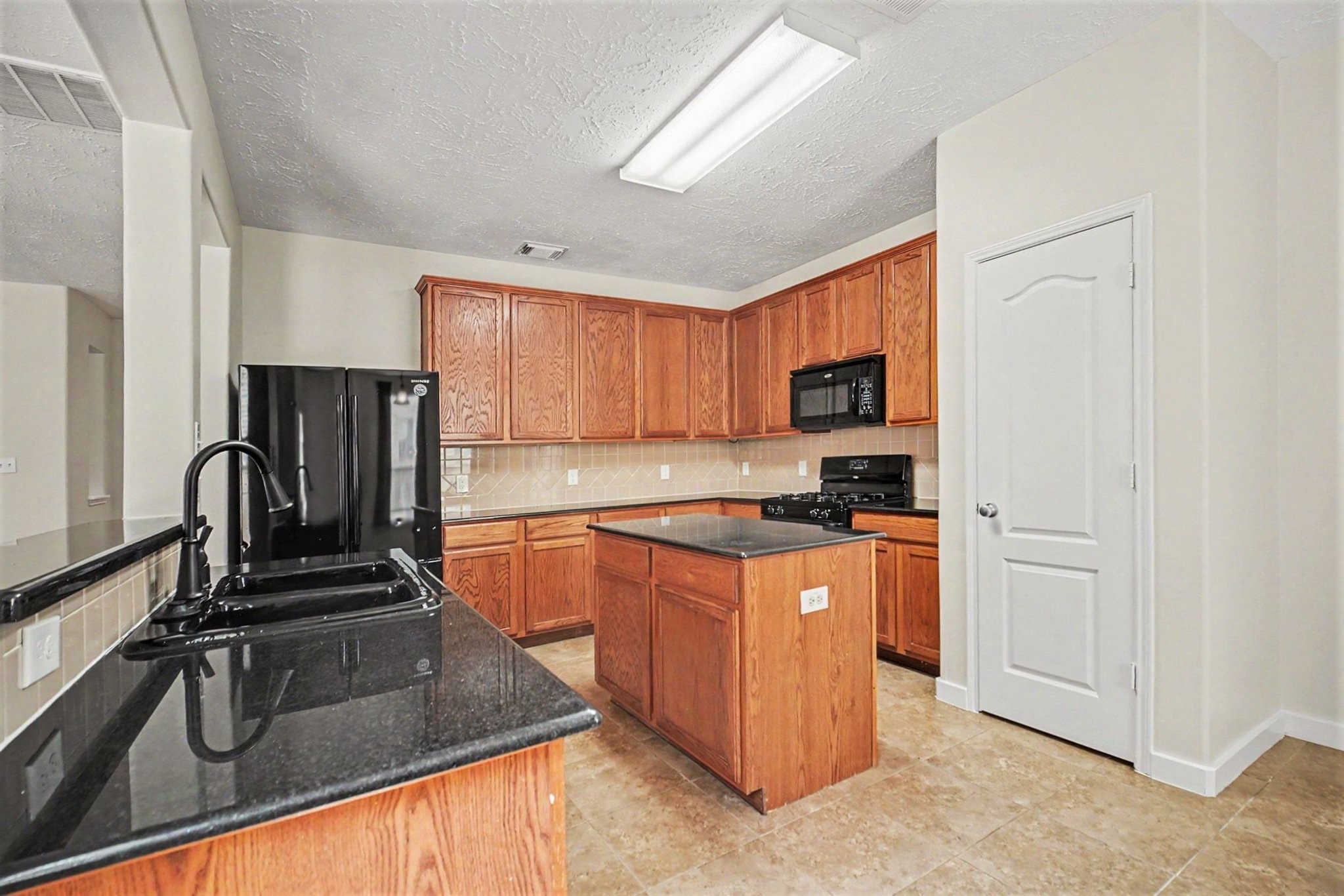 7419 Hollister Ridge Houston, TX 77040 - Photo 7 of 27 Kitchen features an island and black appliances.