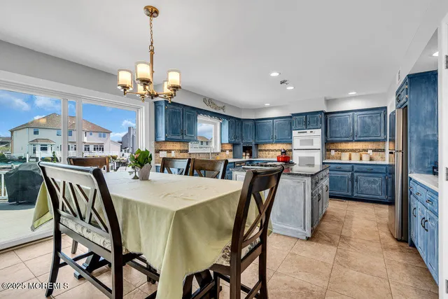 a view of a dining room and livingroom with furniture a chandelier and kitchen view