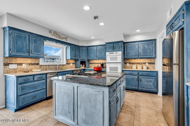 a kitchen with granite countertop a refrigerator stove top oven and wooden cabinets
