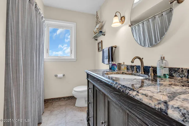 a bathroom with a granite countertop sink a toilet and mirror