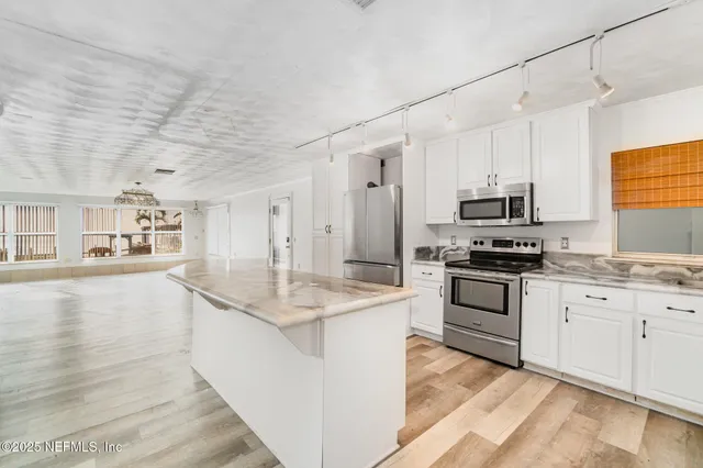 a kitchen with stainless steel appliances kitchen island granite countertop a stove a sink and a refrigerator