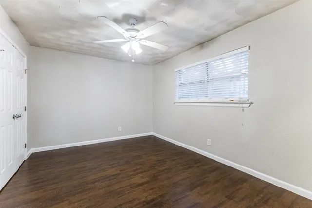 an empty room with wooden floor chandelier fan and windows