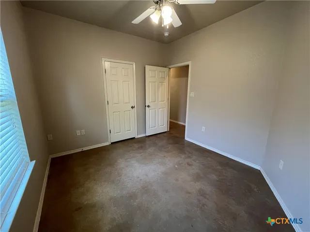 en empty room with a ceiling fan and window