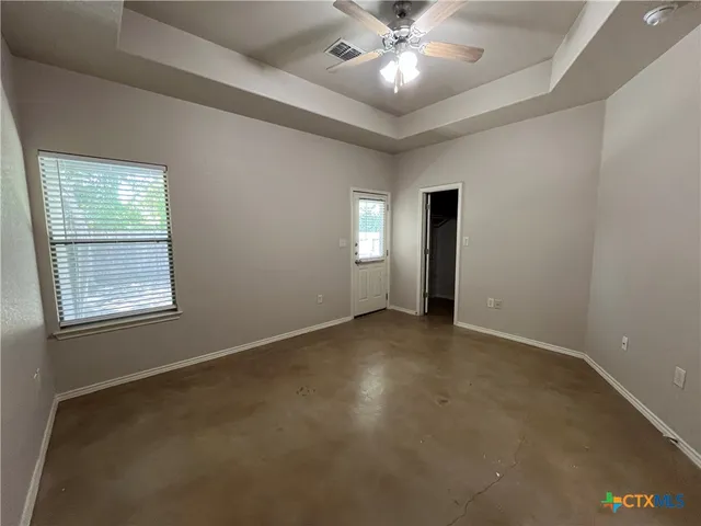 an empty room with windows and fan