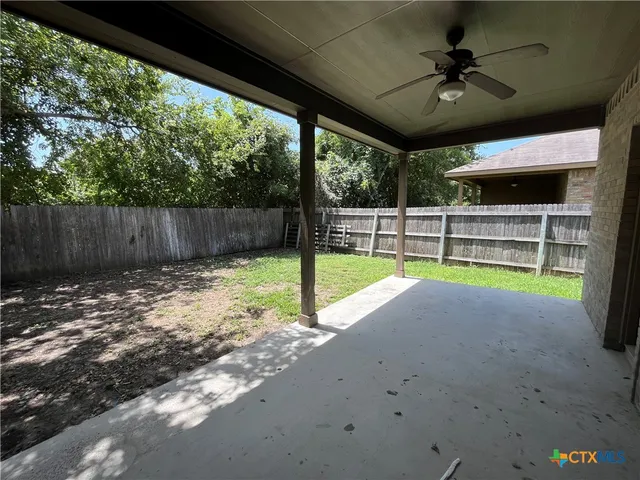 a view of a backyard with a large tree and wooden fence